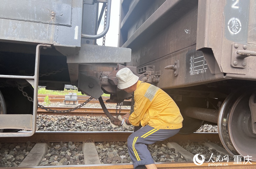 調車員彎腰將貨車間的風管拉開。 人民網記者 胡虹攝